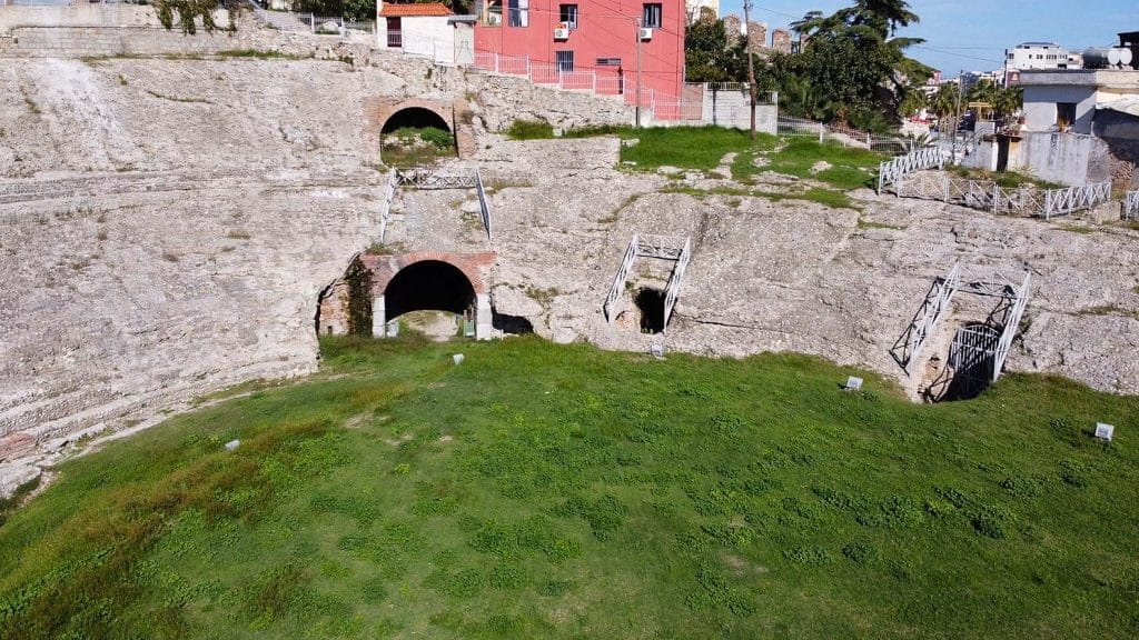 Tourists exploring the historic seats of the Roman amphitheater in Durrës